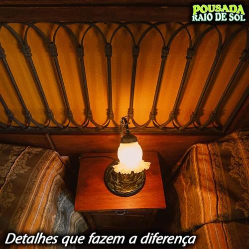 a lamp on a table next to a bed at Pousada Raio de Sol in Jaguarão