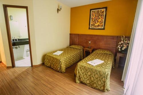 a hotel room with two beds and a sink at Pousada Raio de Sol in Jaguarão