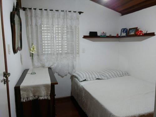 a bedroom with a bed and a window with a table at Casa acolhedora. in Maresias