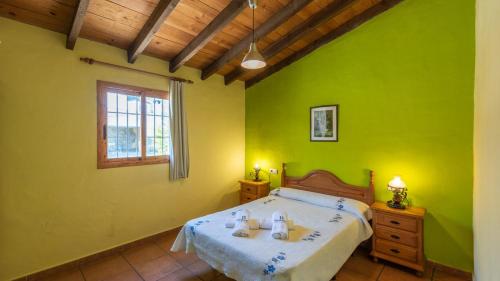 a bedroom with a bed with green walls and a window at Casa Alejandro Almachar by Ruralidays in Almáchar