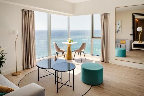 
a living room with a table and chairs and a balcony at Arrecife Gran Hotel & Spa in Arrecife
