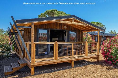 a small wooden house with a porch and some flowers at Camping Montana Parc - Gassin Golfe de St Tropez - Maeva in Gassin