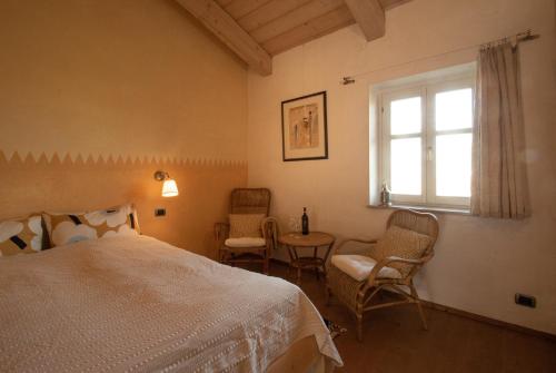 a bedroom with a bed and chairs and a window at Ferrarotti in Clavesana