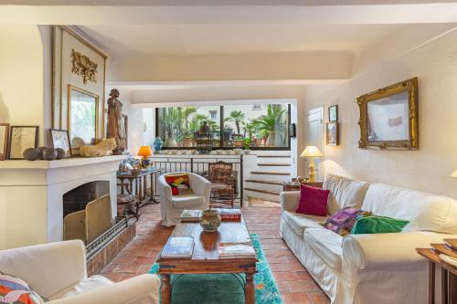 a living room with white furniture and a fireplace at La Maison du Prince in Grimaud