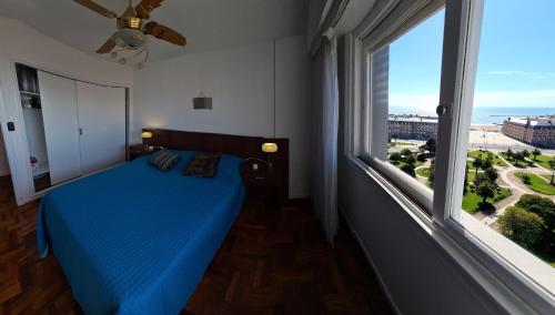 a bedroom with a blue bed and a large window at EdenMDQ in Mar del Plata