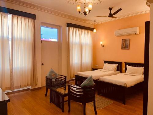 a bedroom with two beds and a table and chairs at Hotel Glitz Jaipur in Jaipur