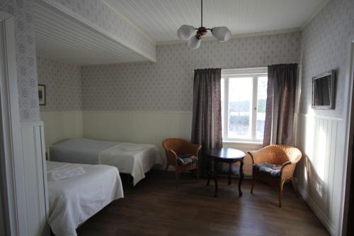 a room with two beds and a table and a window at Kauppilan Matkailutalo in Ikaalinen