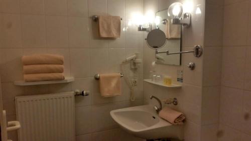 ein Badezimmer mit einem Waschbecken, einem Spiegel und Handtüchern in der Unterkunft Landhotel Albrecht in Missen-Wilhams