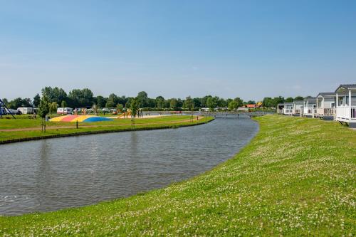 a body of water with houses and a park at Camping de Vogel in Hengstdijk