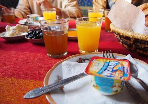 un tavolo con un piatto di cibo e due bicchieri di succo d'arancia di M'hamid Desert Camp Tours a M'Hamid