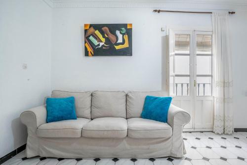 a white couch in a living room with blue pillows at Casa Romero in Vejer de la Frontera