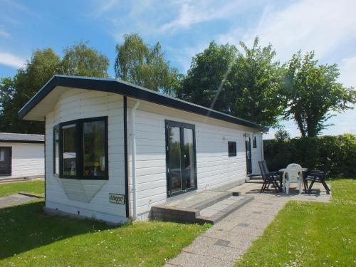a small white shed with a table and chairs at Camping de Vogel in Hengstdijk