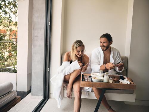 a man and a woman sitting at a table looking at their cell phones at Contessina Suites & Spa - Adults Only in Tsilivi