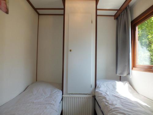 two beds in a small room with a window at Camping de Vogel in Hengstdijk
