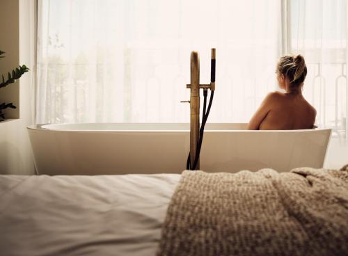 a woman sitting in a bath tub in a bedroom at Contessina Suites & Spa - Adults Only in Tsilivi
