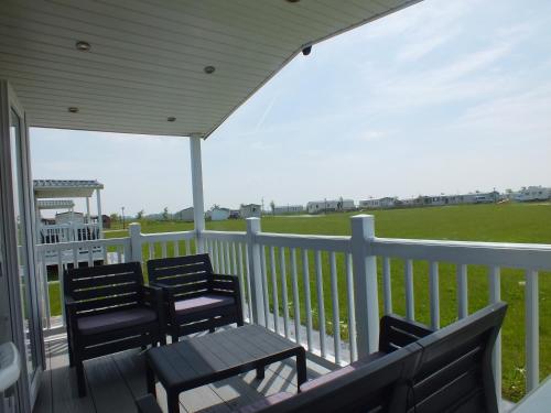 two chairs and a table on a porch with a view of a field at Camping de Vogel in Hengstdijk