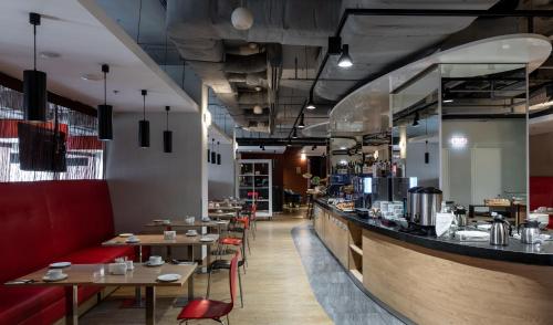 a restaurant with wooden tables and red chairs at Ramada Encore Kyiv in Kyiv