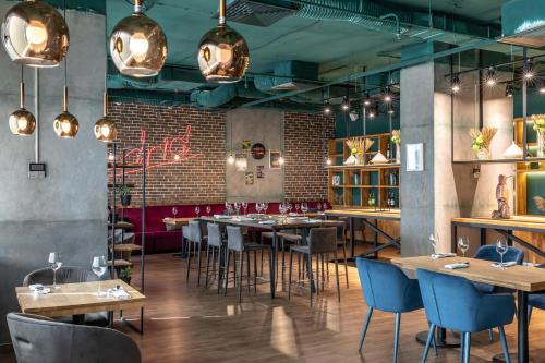 restauracja z drewnianymi stołami i niebieskimi krzesłami w obiekcie Ramada Encore Kyiv w Kijowie