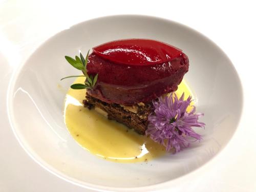 a piece of cake on a white plate with a flower at Hotel Du Lac in Molveno