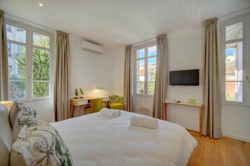 une chambre avec un lit blanc, un bureau et des fenêtres dans l'établissement IMMOGROOM - Magnificent 180m duplex apartment - Parking - Air conditioning, à Cannes