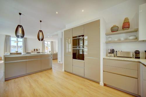 une cuisine avec des armoires blanches et un plancher en bois dans l'établissement IMMOGROOM - Magnificent 180m duplex apartment - Parking - Air conditioning, à Cannes
