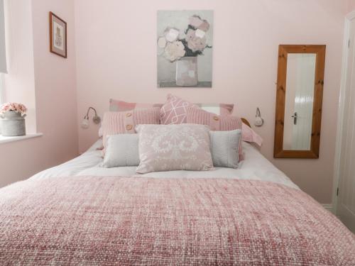 ein Schlafzimmer mit einem Bett mit einer rosa Decke und Kissen in der Unterkunft Gabby's Garden Cottage in Hull