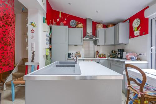 - une cuisine avec des placards blancs et des murs rouges dans l'établissement Spinelle - Maison 3 chambres avec jardin - plage à 100 m, au Crotoy