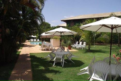 un grupo de sillas y sombrillas blancas en un patio en Cond Solar Lagoa dos Pássaros en Praia do Forte