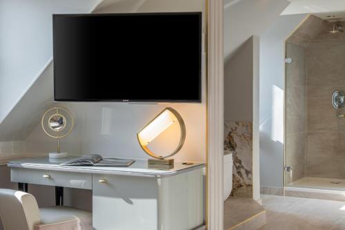 a room with a desk with a television on a wall at Hôtel Elysia in Paris