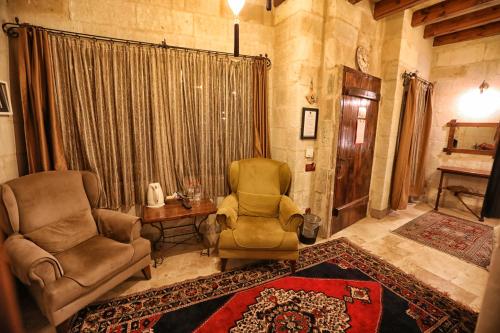 a living room with two chairs and a table at Göreme Cave Suites in Goreme