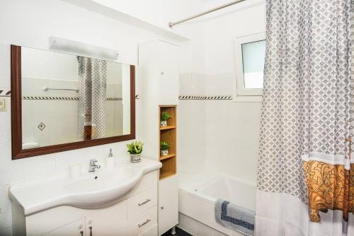 a bathroom with a sink and a tub and a mirror at Aristotelis Apartment Lakithra-Lydia in Lakíthra