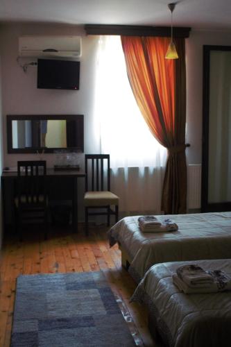 a bedroom with two beds and a desk and a window at Garni Hotel City in Kruševac