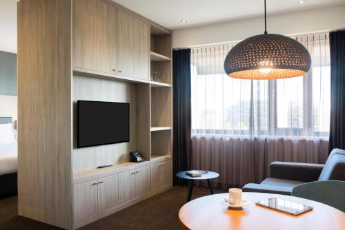 een woonkamer met een tv en een bank en een tafel bij Adagio Amsterdam City South in Amstelveen