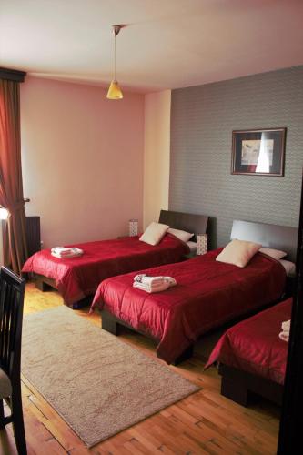 a hotel room with three beds with red sheets at Garni Hotel City in Kruševac