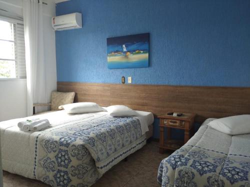a bedroom with two beds and a blue wall at Pousada Aconchego de Minas in Juiz de Fora