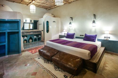 a bedroom with a large bed with purple pillows at Riad Madu in Merzouga