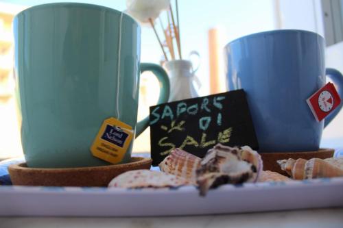 two cups and a plate of food with two cookies at Sapore di Sale - Sicily Rooms in Siracusa