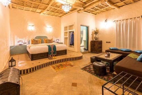 a bedroom with a bed and a living room at Riad Madu in Merzouga