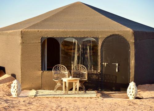 a tent with a table and chairs in it at Riad Madu in Merzouga