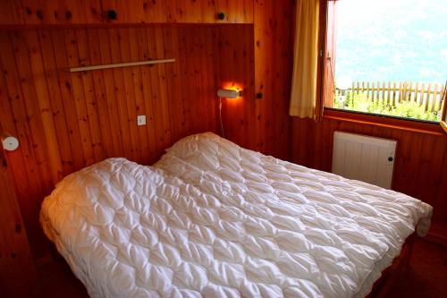 1 dormitorio con 1 cama blanca y ventana en Eanta SUNNY & MOUNTAIN chalet 10 pers by Alpvision Résidences, en Veysonnaz