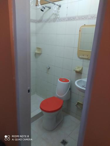 ein Badezimmer mit einer roten Toilette und einem Waschbecken in der Unterkunft Alcobas cerca al Éxito San Fernando in Cali