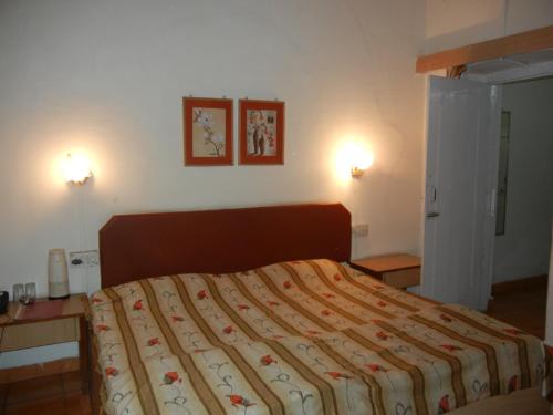 - une chambre avec un lit et deux lumières sur le mur dans l'établissement Hotel Grand Barrack, à Khandwa