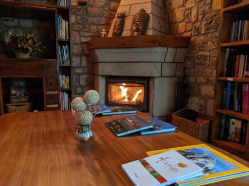 a fireplace in a living room with a wooden table at Hotel Rural El Rexacu in Bobia de Arriba