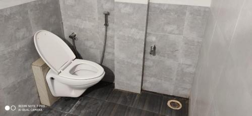 a bathroom with a white toilet in a stall at Whispering rocks hampi in Hampi