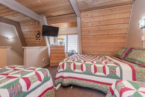 a bedroom with two beds and a flat screen tv at Bigwood W #90 in Mammoth Lakes