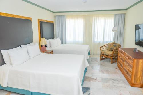 a hotel room with two beds and a television at Samba Vallarta All Inclusive in Nuevo Vallarta 