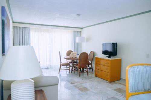 a living room with a tv and a table with chairs at Samba Vallarta All Inclusive in Nuevo Vallarta