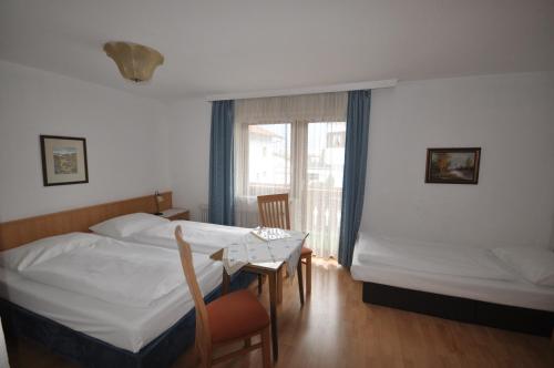 a bedroom with two beds and a table and a window at Gästehaus Pension Edelweiss in Kolsass