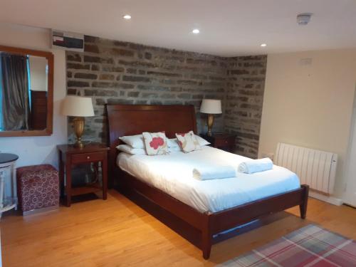 a bedroom with a bed and a brick wall at Bryncarnedd Farmhouse in Aberystwyth