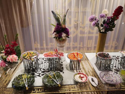 a table with plates of food and flowers on it at Al Andalus Palace 1 Hotel in Al Madinah